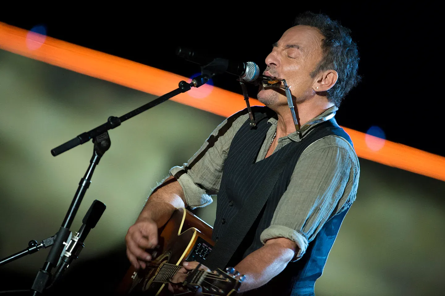 Bruce Springsteen en concert avec une guitare acoustique et un harmonica