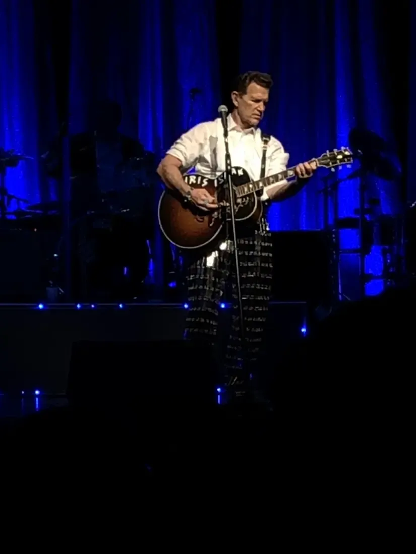 Chris Isaak en performance scénique avec guitare acoustique