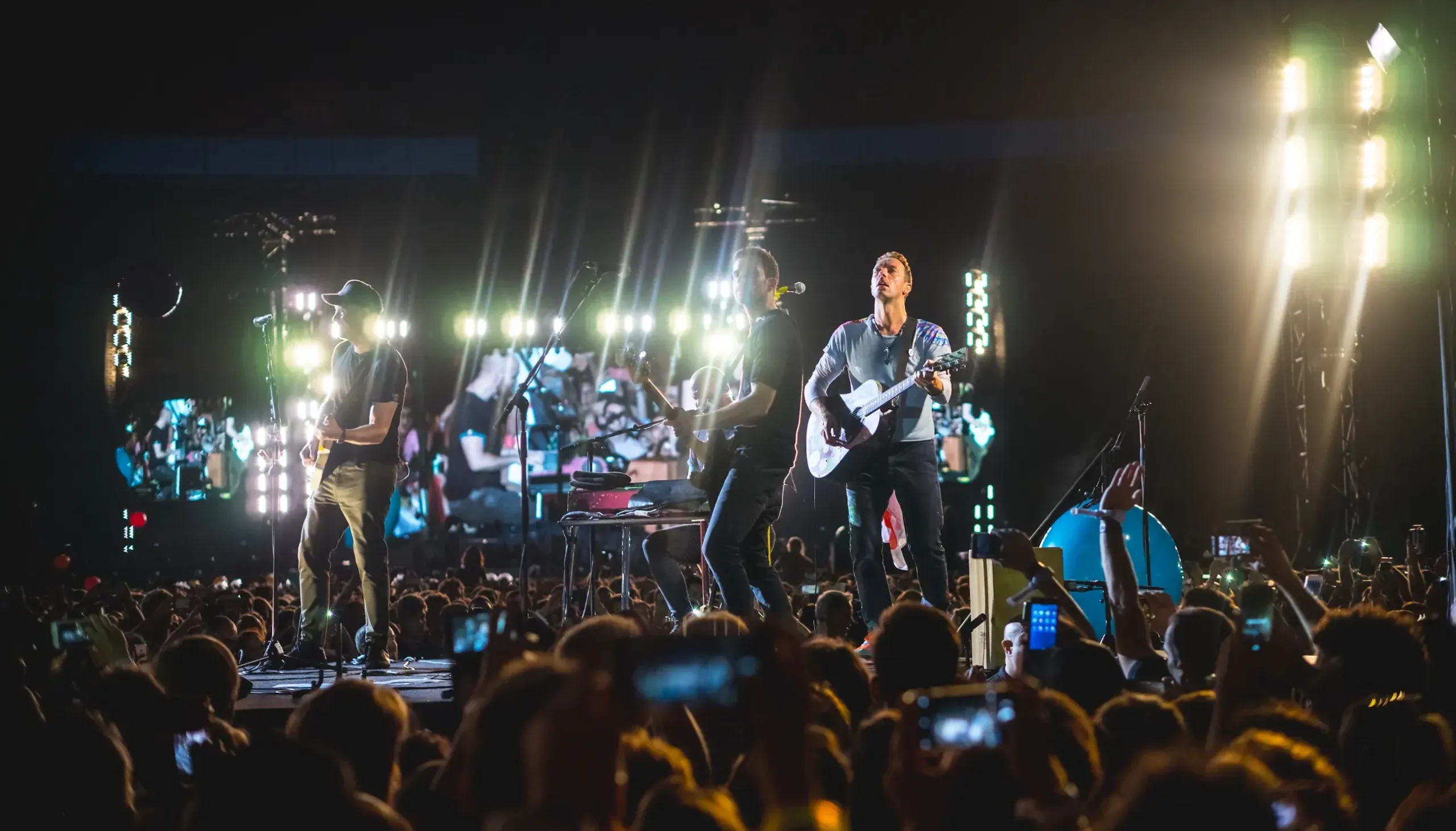 Coldplay en concert avec guitares, lumières et public