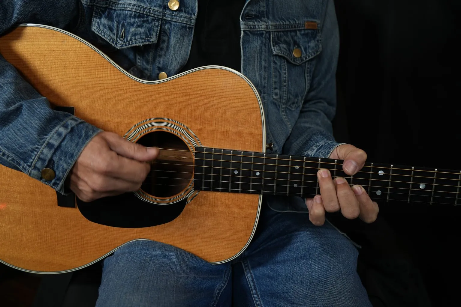 Trois adultes souriants jouant de la guitare ensemble