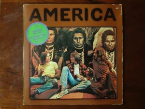 Pochette de l’album "America" sorti en 1971, avec le trio assis devant une fresque amérindienne.
