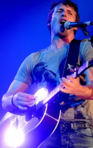 James Blunt en concert, chantant et jouant de la guitare acoustique sur scène.