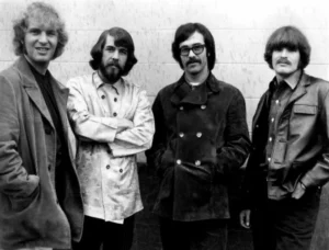Portrait en noir et blanc des membres de Creedence Clearwater Revival posant devant un mur
