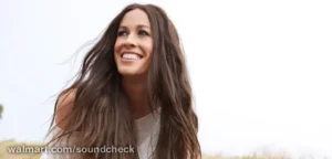 Alanis Morissette souriante en plein air dans un portrait promotionnel naturel