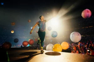 Le chanteur de Coldplay sur scène au milieu de ballons colorés et d’un public en liesse