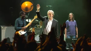 Eric Clapton saluant la foule à la fin d’un concert, entouré de ses musiciens