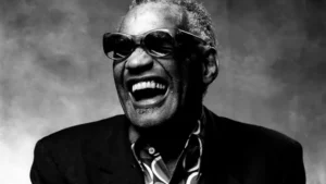 Portrait noir et blanc de Ray Charles éclatant de rire avec ses lunettes iconiques