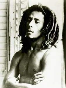 Portrait en noir et blanc de Bob Marley torse nu, bras croisés, regard pensif