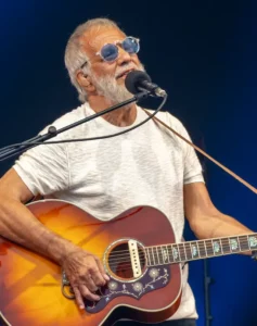 Cat Stevens, aussi connu sous le nom Yusuf Islam, jouant de la guitare acoustique sur scène lors d’un concert