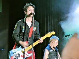 Billie Joe Armstrong et Mike Dirnt de Green Day en concert, jouant avec énergie sur scène.