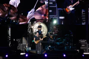 Le groupe The Police en concert, Sting jouant de la basse et Stewart Copeland à la batterie devant un gong.