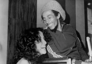 Bob Marley souriant et discutant avec Martha Velez en 1976, photographie en noir et blanc.